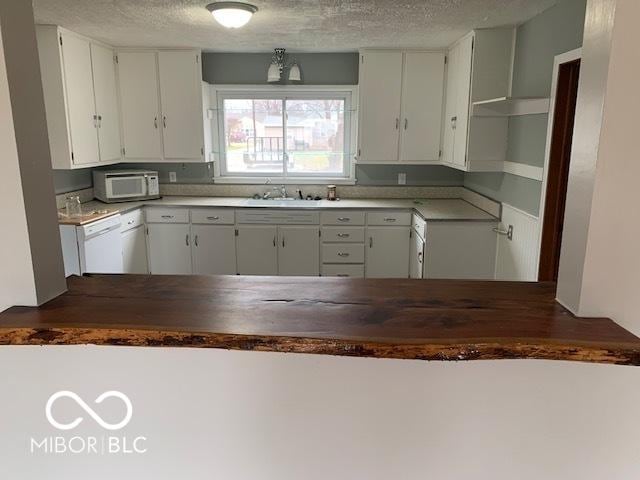 kitchen featuring white cabinets, a textured ceiling, white appliances, and sink