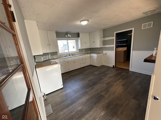 kitchen with sink, white cabinets, a textured ceiling, and washer / dryer