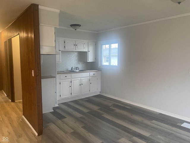 kitchen featuring sink, backsplash, crown molding, hardwood / wood-style floors, and white cabinets