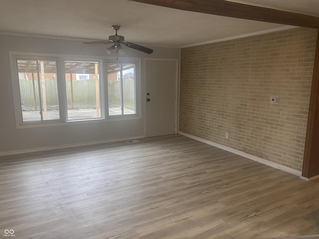 spare room with ceiling fan, brick wall, and ornamental molding