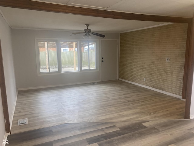 spare room with ceiling fan, crown molding, brick wall, and hardwood / wood-style flooring