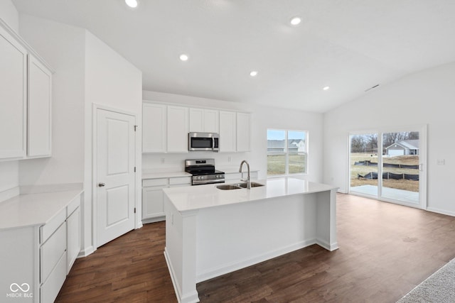 kitchen featuring stainless steel appliances, a center island with sink, dark wood-style flooring, and light countertops