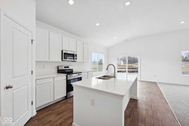 kitchen featuring an island with sink, a sink, white cabinetry, appliances with stainless steel finishes, and vaulted ceiling