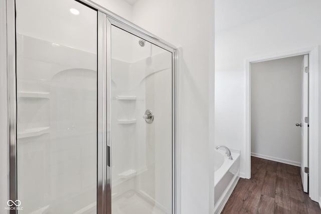 full bathroom with baseboards, a garden tub, wood finished floors, and a shower stall