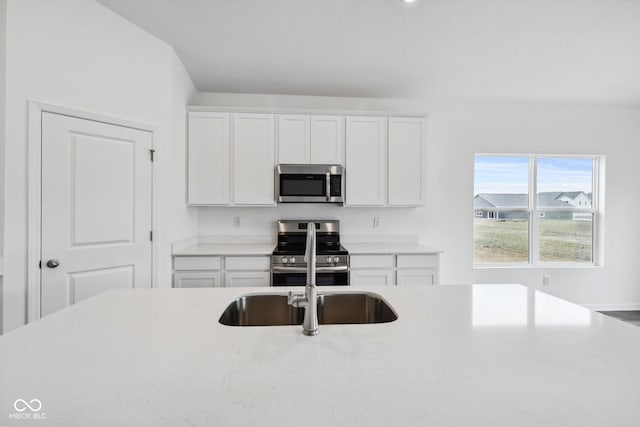 kitchen featuring a sink, white cabinets, light stone counters, and stainless steel appliances