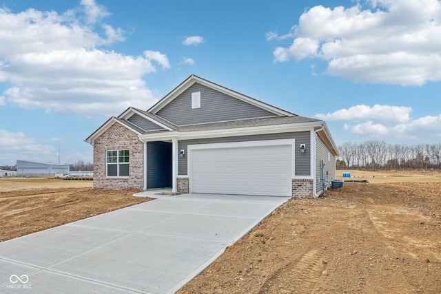 view of front of property with brick siding, cooling unit, driveway, and an attached garage