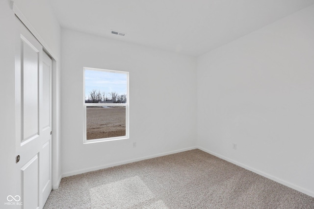 carpeted empty room featuring visible vents and baseboards