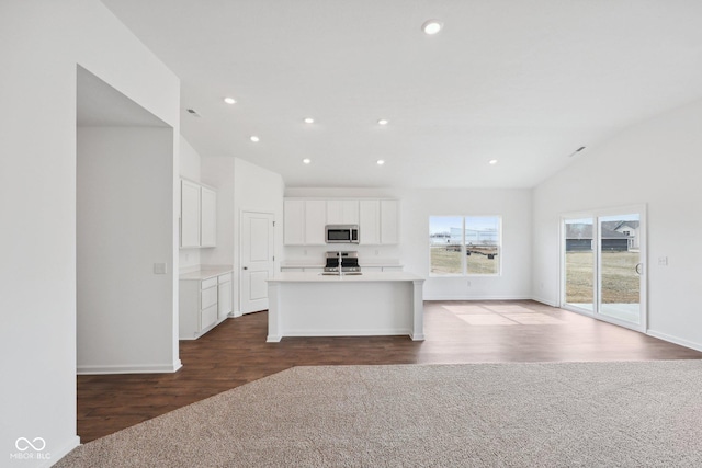 kitchen with open floor plan, light countertops, lofted ceiling, appliances with stainless steel finishes, and white cabinetry