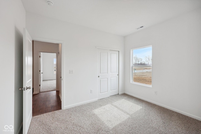 unfurnished bedroom featuring a closet, visible vents, baseboards, and carpet