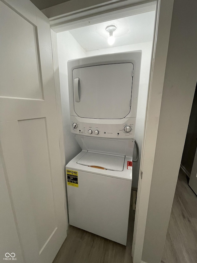 laundry room with light wood-type flooring and stacked washer and dryer