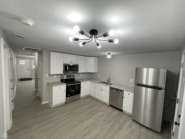 kitchen featuring light stone countertops, white cabinetry, sink, stainless steel appliances, and a notable chandelier