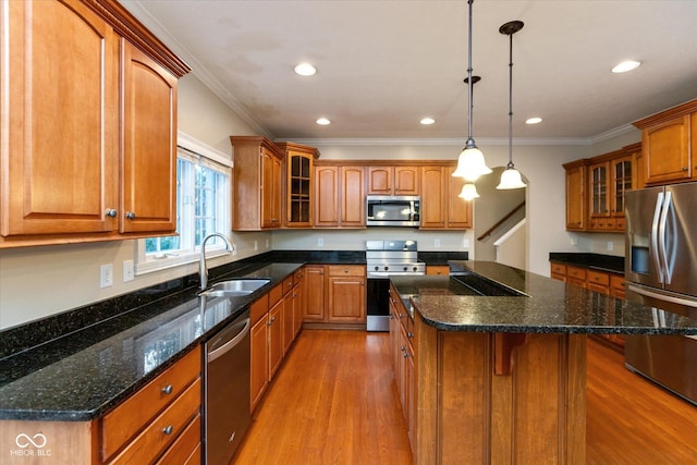 kitchen with pendant lighting, a center island, sink, ornamental molding, and stainless steel appliances