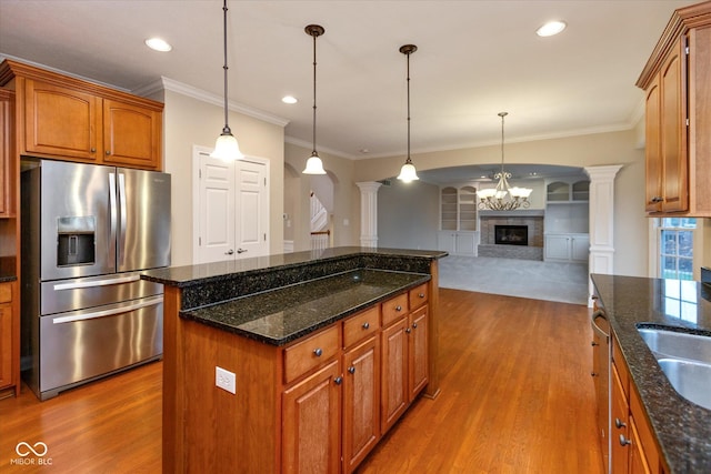 kitchen featuring stainless steel fridge with ice dispenser, decorative columns, pendant lighting, and dark stone countertops