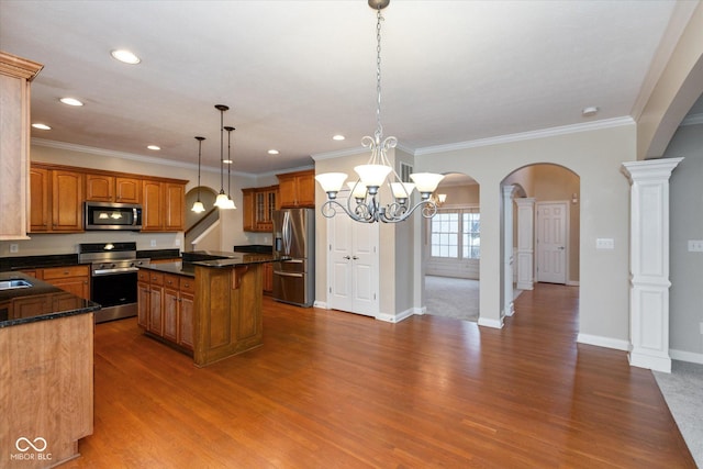 kitchen with ornate columns, a center island, stainless steel appliances, decorative light fixtures, and ornamental molding