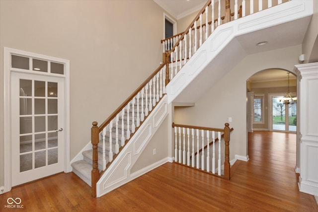 stairway featuring wood-type flooring, a high ceiling, and ornamental molding