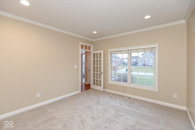 spare room with crown molding, french doors, and light colored carpet