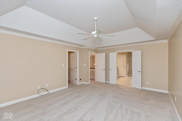 unfurnished bedroom with light carpet, crown molding, vaulted ceiling, ceiling fan, and a tray ceiling