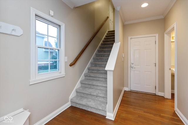 staircase featuring hardwood / wood-style floors, crown molding, and a healthy amount of sunlight