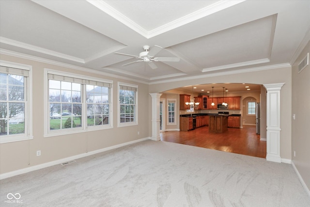 unfurnished living room featuring ceiling fan, dark carpet, ornate columns, and crown molding