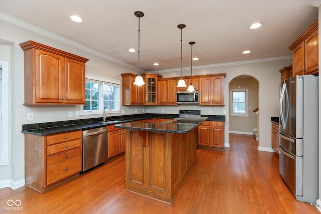 kitchen featuring a center island, sink, crown molding, decorative light fixtures, and stainless steel appliances