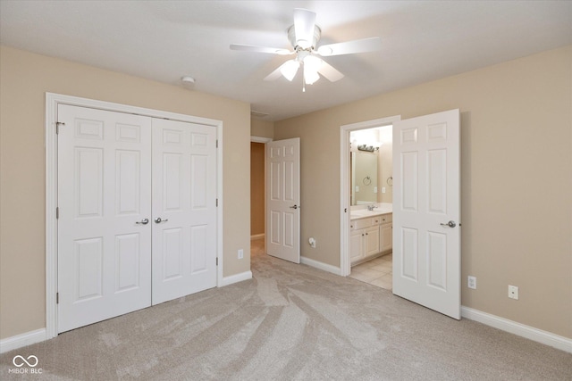 unfurnished bedroom featuring ceiling fan, ensuite bathroom, light carpet, and a closet