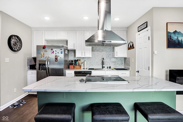 kitchen with white cabinetry, light stone counters, wall chimney range hood, and stainless steel refrigerator with ice dispenser