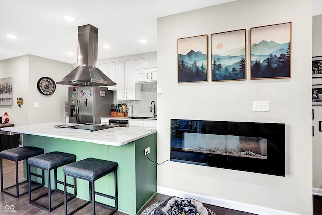 kitchen featuring a kitchen bar, appliances with stainless steel finishes, island range hood, sink, and white cabinetry