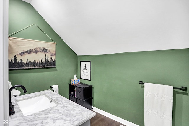 bathroom with vanity, hardwood / wood-style flooring, and vaulted ceiling