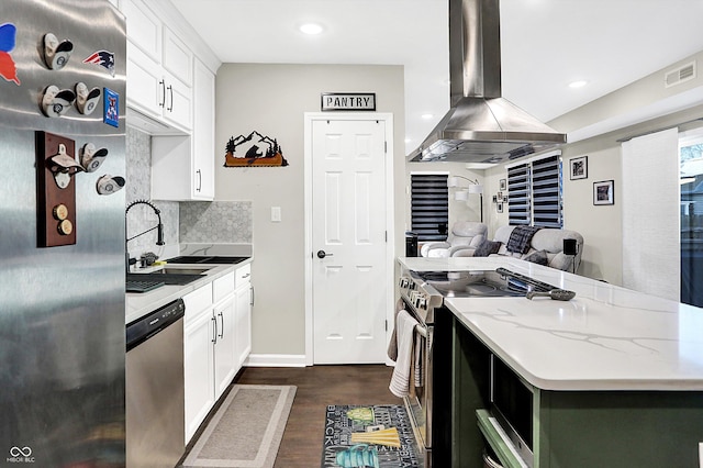 kitchen with white cabinets, decorative backsplash, appliances with stainless steel finishes, light stone counters, and island exhaust hood