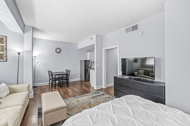 bedroom featuring dark hardwood / wood-style flooring, a textured ceiling, and stainless steel refrigerator