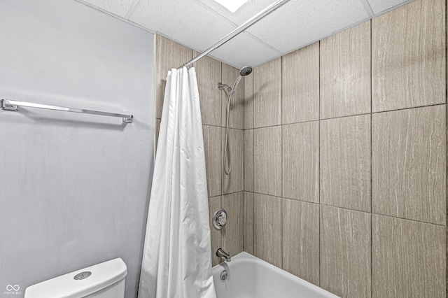 bathroom featuring shower / tub combo, toilet, and a drop ceiling