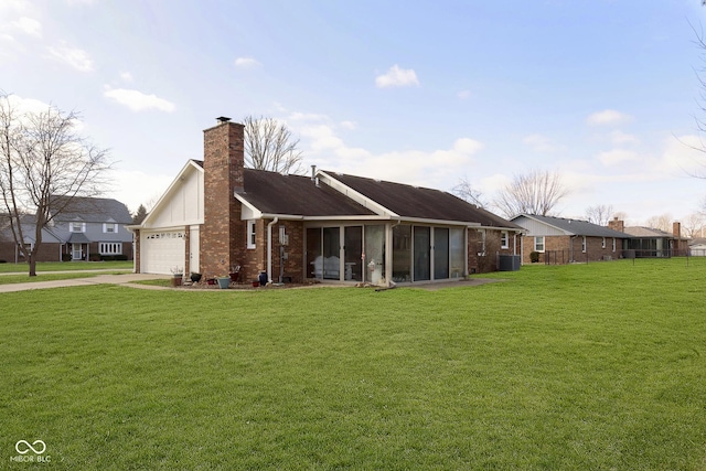 back of house with a sunroom, a garage, and a yard