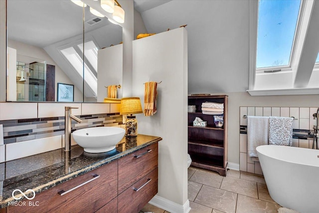 bathroom with vanity, a bath, vaulted ceiling with skylight, tile patterned flooring, and tasteful backsplash