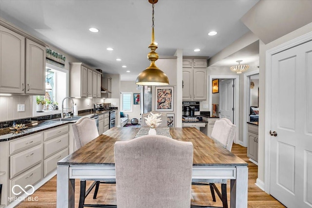 kitchen featuring gray cabinetry, stainless steel electric stove, hanging light fixtures, light wood-type flooring, and tasteful backsplash