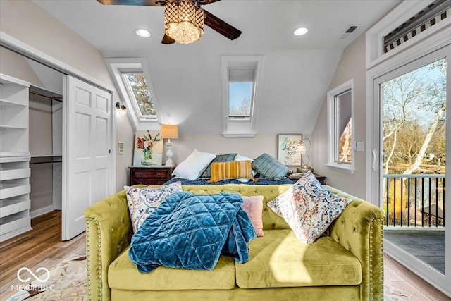 bedroom with access to exterior, ceiling fan, wood-type flooring, multiple windows, and a closet