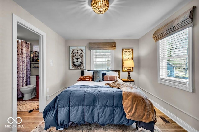 bedroom with hardwood / wood-style floors and ensuite bath