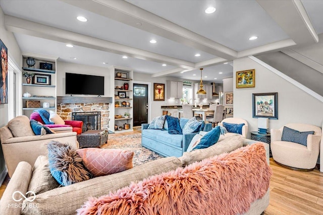 living room with a fireplace, beam ceiling, and light hardwood / wood-style floors