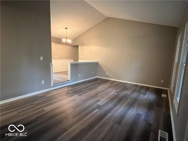 unfurnished living room with dark hardwood / wood-style floors, lofted ceiling, and a notable chandelier