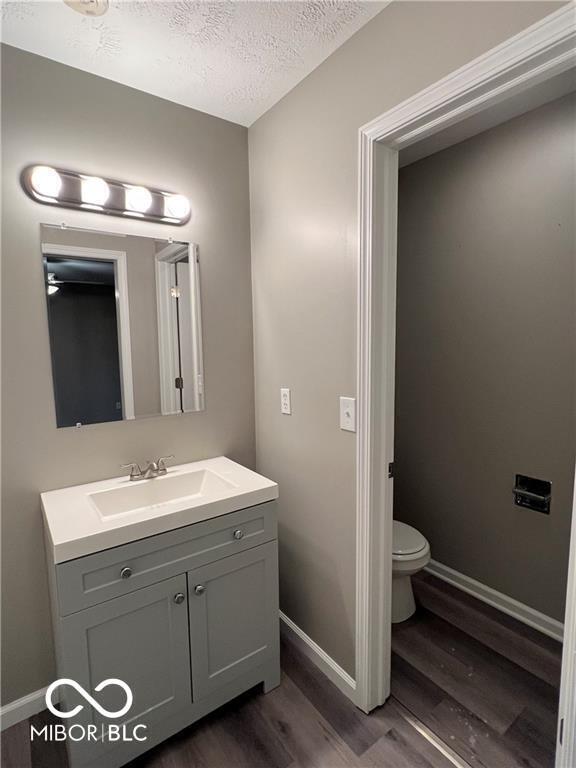 bathroom with vanity, wood-type flooring, a textured ceiling, and toilet