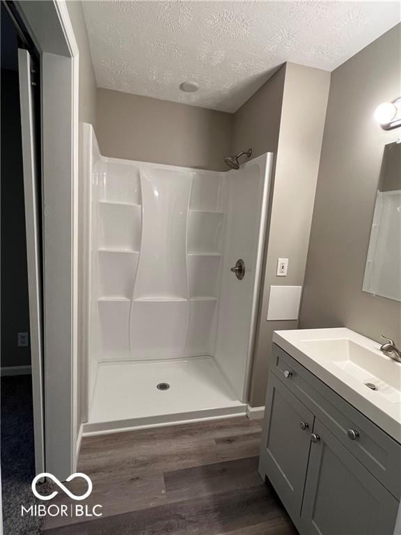 bathroom with vanity, a shower, a textured ceiling, and hardwood / wood-style flooring