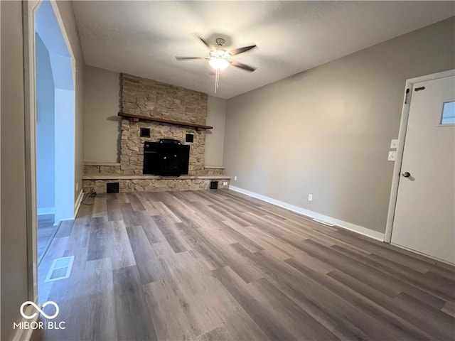 unfurnished living room featuring a stone fireplace, ceiling fan, and hardwood / wood-style floors