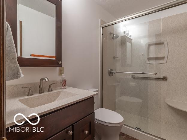 bathroom with vanity, toilet, and a shower with door