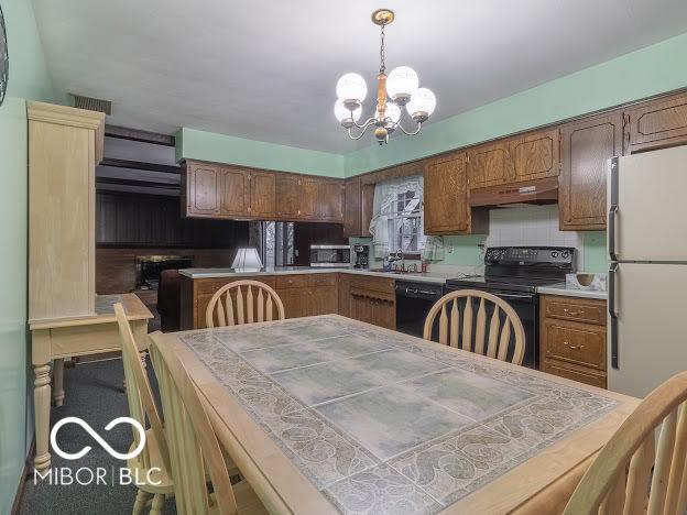 kitchen with sink, tile counters, hanging light fixtures, an inviting chandelier, and black appliances