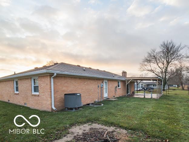 back house at dusk with a yard and cooling unit