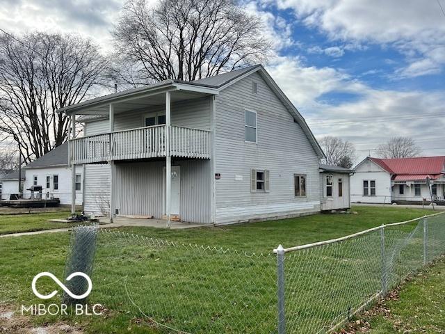 back of property with a lawn and a balcony