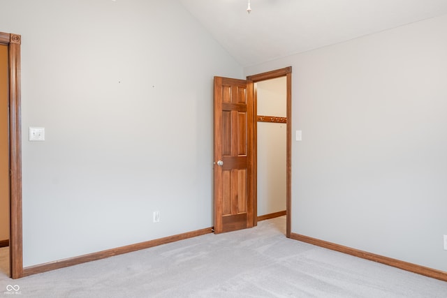 carpeted spare room featuring vaulted ceiling