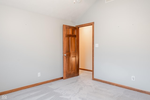 carpeted spare room featuring vaulted ceiling