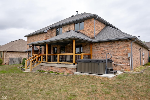 rear view of property featuring a yard and a hot tub