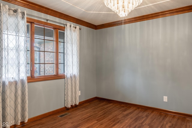 empty room with hardwood / wood-style flooring, a notable chandelier, crown molding, and a wealth of natural light