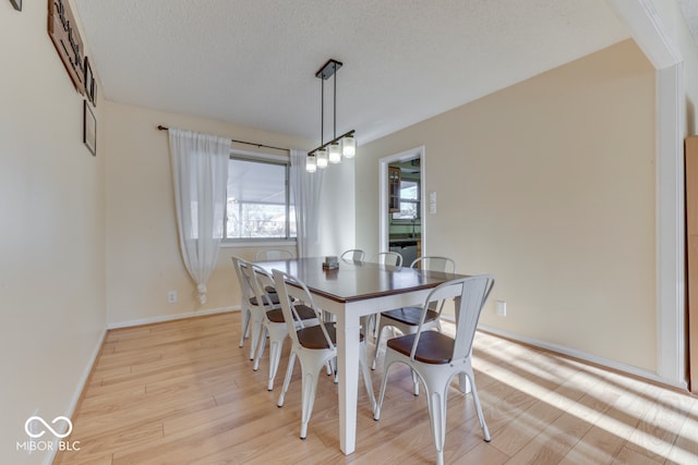 dining area with light hardwood / wood-style flooring and a textured ceiling